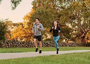 Couple running through park together in Bloom townhomes community by AVJennings located in Wollert VIC 3750. Townhouses for sale, Wollert. 